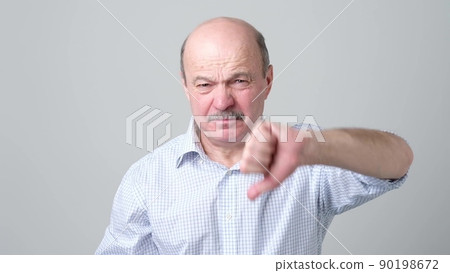 Mature caucasian man showing his dislike and disappointment with thumbs down Mature caucasian man showing his dislike and disappointment with thumbs down 90198672