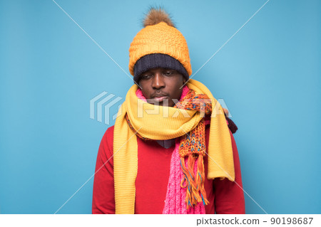 African man in several hats and scarfs being sad or feeling cold African man in several hats and scarfs being sad or feeling cold 90198687