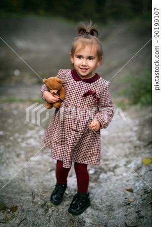 Little girl holding a teddy bear. Portrait of a little girl 90199107