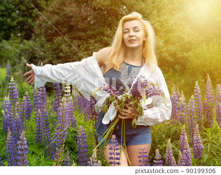 Woman walks in the garden full of lupines Woman walks in the garden full of lupines 90199306