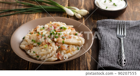 Potato dumplings with sour cream on the wooden table. Traditional ukrainian food. Varenyky, vareniki, pierogi, pyrohy - dumplings with filling. Potato dumplings with sour cream on the wooden table. Traditional ukrainian food. Varenyky, vareniki, pierogi, pyrohy - dumplings with filling. 90207555