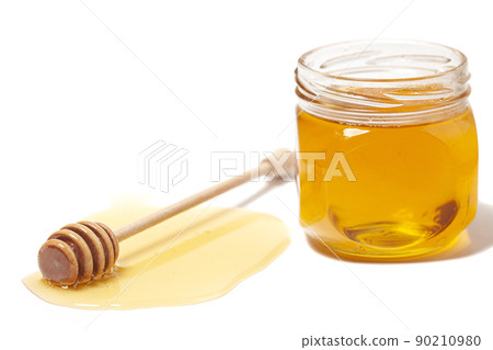 Honey dripping from honey dipper in glass jar. Healthy food concept Honey dripping from honey dipper in glass jar. Healthy food concept 90210980