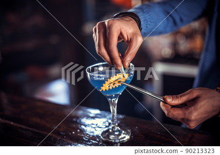 Charismatic tapster pouring fresh alcoholic drink into the glasses in the nightclub Charismatic tapster pouring fresh alcoholic drink into the glasses in the nightclub 90213323