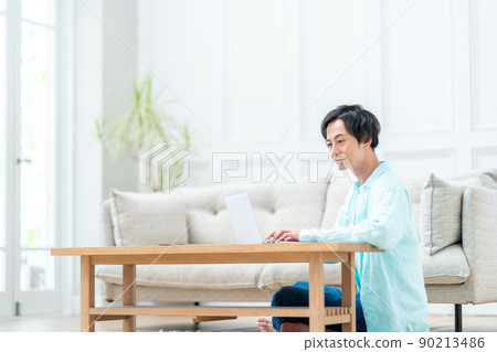 一個男人在客廳裡操作筆記本電腦。 90213486