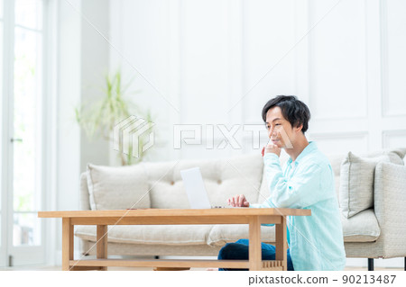 A man operating a laptop in the living room. A man operating a laptop in the living room. 90213487