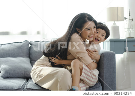 Happy Asian tender son hugging mother on mother's day during holiday celebration at home. Happy Asian tender son hugging mother on mother's day during holiday celebration at home. 90214254