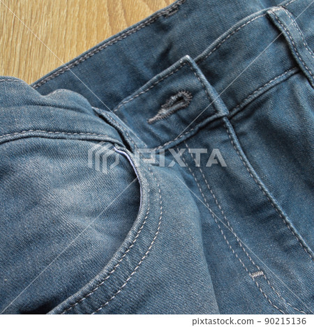 Zipper pocket and buttons close-up detail of light blue jeans 90215136