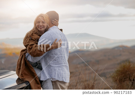 Beautiful cheerful woman embracing her beloved man and smiling to camera outdoors 90217183