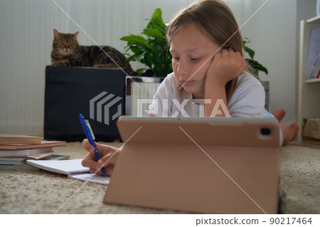 a girl does her homework on a tablet 90217464