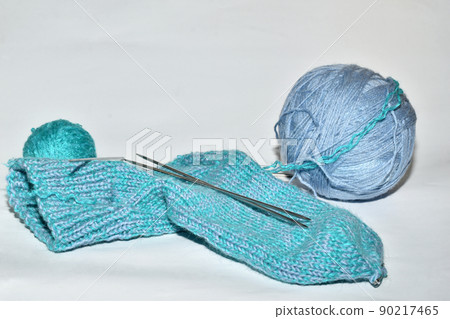 Woolen knitted sock and a ball of blue woolen threads. 90217465