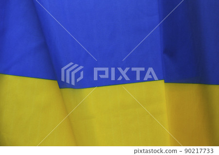 Close up shot of ruffled Ukrainian yellow and blue flag with a lot of copy space for text. Textured background. 90217733