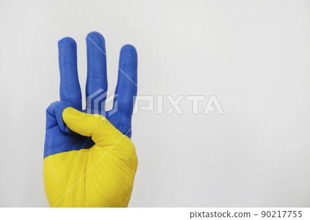Man's hand painted in colors of Ukrainian flag showing a traditional trident hand gesture symbolizing national coat of arms. Copy space, close up, background. Man's hand painted in colors of Ukrainian flag showing a traditional trident hand gesture symbolizing national coat of arms. Copy space, close up, background. 90217755