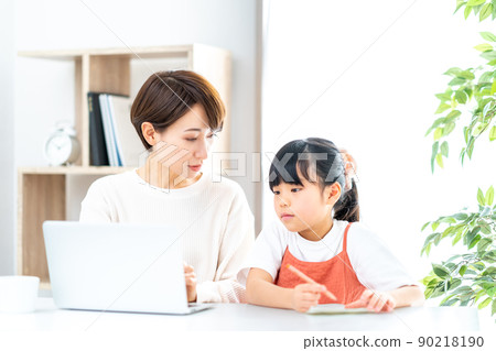 一個在客廳遠程辦公的媽媽和一個在身邊讀書的女兒 90218190