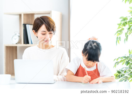 一個在客廳遠程辦公的媽媽和一個在身邊讀書的女兒 90218192