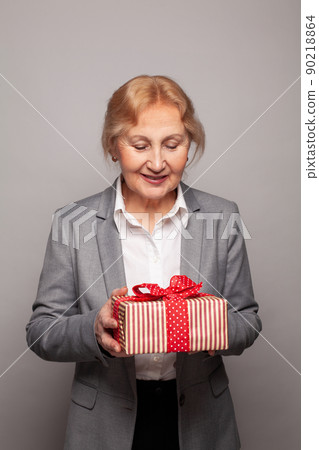 Cheerful woman 60 s years old holding red gift box present portrait Cheerful woman 60 s years old holding red gift box present portrait 90218864