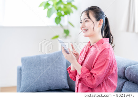 在她的智能手機上網上購物的年輕女人 在她的智能手機上網上購物的年輕女人 90219473