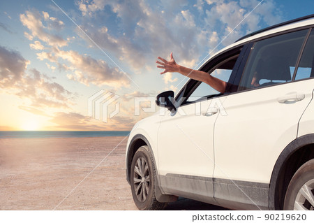 Toward adventure! Guy relaxing and enjoying road trip. Happy man rides into the sunset in car. 90219620