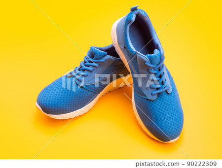 sporty blue sneakers pair on yellow background, footgear 90222309