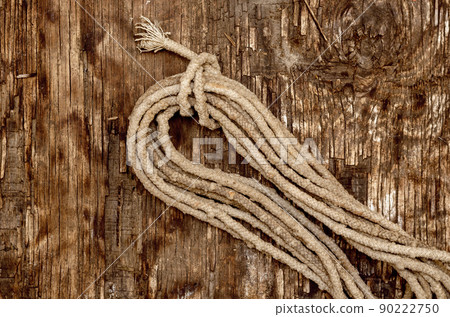 Coil of old rope on a dark wooden background. Worn, dirty rope. 90222750