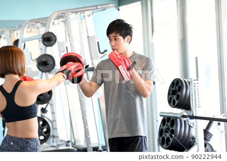 Male trainer and female customer holding a mitt 90222944