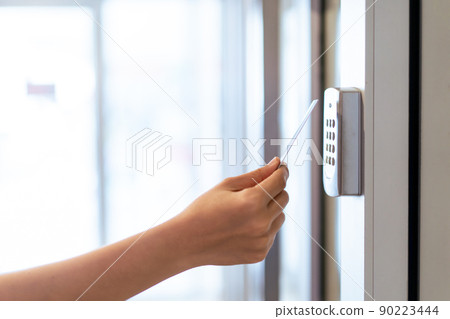 Unrecognizable woman using a keycard or pass card to unlock and access the security door at apartment. Security system for residential area. Personal identification system. 90223444