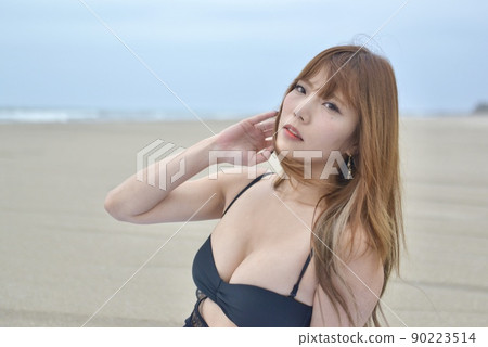 A young woman in a black bikini posing on a sandy beach A young woman in a black bikini posing on a sandy beach 90223514