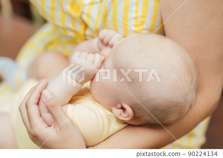 Newborn Baby Skin Care. Close up Mother holding newborn baby in hands on nature background. Outdoor portrait of mother with infant child son. 90224134