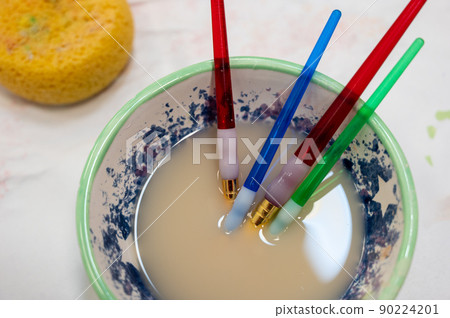 Selection of paint brushes in a bowl of dirty water from an art project 90224201