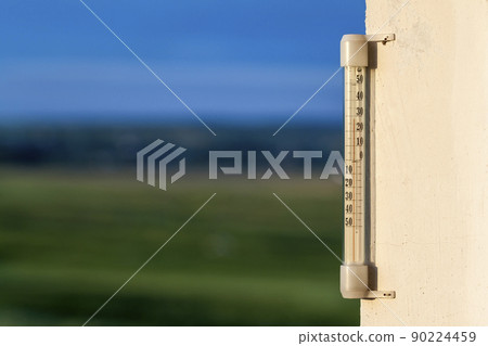 Thermometer celsius showing warm temperature on blurred green background. Weather forecast concept. Thermometer celsius showing warm temperature on blurred green background. Weather forecast concept. 90224459