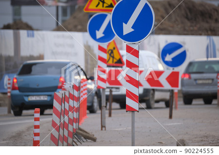 Roadworks warning traffic signs of construction work on city street and slowly moving cars 90224555