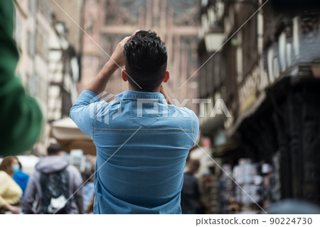Portrait on back view of an taking a photo with his smartphone Portrait on back view of an taking a photo with his smartphone 90224730