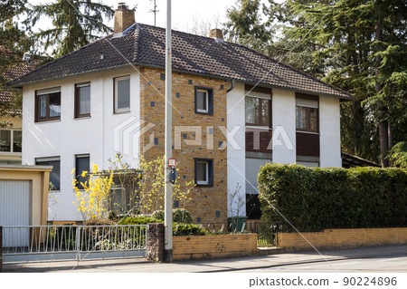 Modern family house on rural street surrounded with green trees 90224896