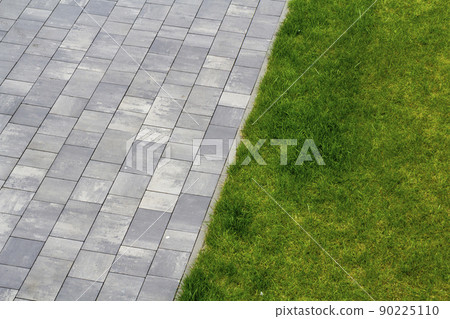 Grey tiles and green grass outdoors Grey tiles and green grass outdoors 90225110