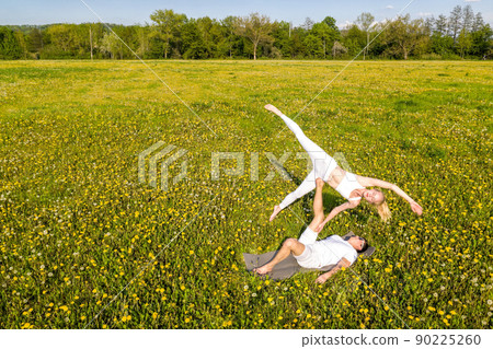 Beautiful young couple doing acro yoga in park. - Stock Photo