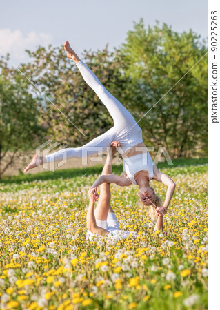 Beautiful young couple doing acro yoga in park. Man lying on grass and balancing woman in his feet. Beautiful young couple doing acro yoga in park. Man lying on grass and balancing woman in his feet. 90225263
