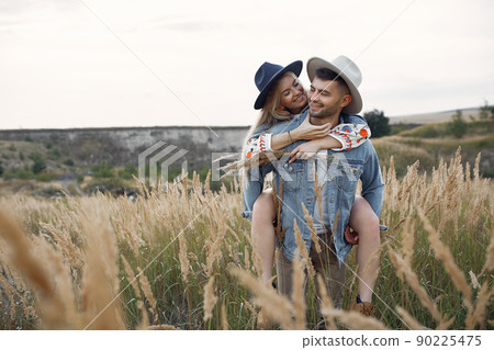 Loving couple in a wheat field. Beautiful blonde in a blue hat. Loving couple in a wheat field. Beautiful blonde in a blue hat. 90225475