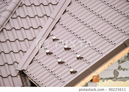 Closeup snow guard for safety in winter on house roof top covered with steel shingles. Tiled covering of building Closeup snow guard for safety in winter on house roof top covered with steel shingles. Tiled covering of building 90225611