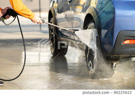 Closeup of male driver washing his car with contactless high pressure water jet in self service car wash. Closeup of male driver washing his car with contactless high pressure water jet in self service car wash. 90225622