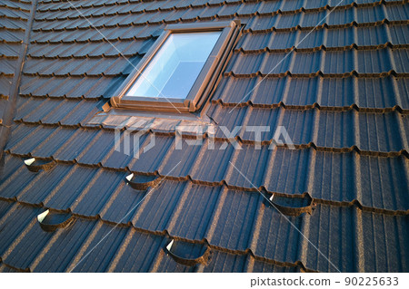 Closeup of attic window on house roof top covered with ceramic shingles. Tiled covering of building Closeup of attic window on house roof top covered with ceramic shingles. Tiled covering of building 90225633