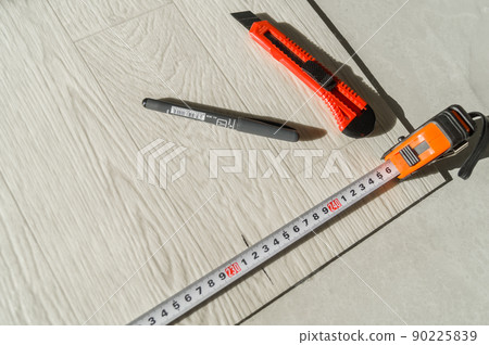 Laying new linoleum on the floor in the room. Tools for mounting and trimming linoleum. Measuring tape measure, stationery knife, marker handle. Selective focus 90225839