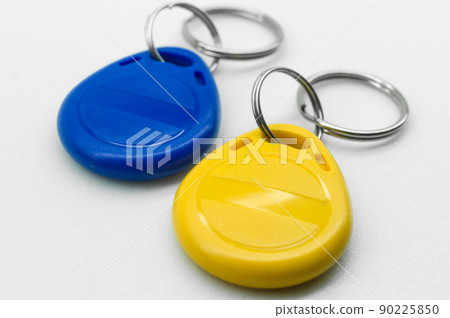 RFID tag key chain. Plastic cloned non-contact electronic radio key for intercom. NFC tag. Ukrain flag colors. Selective focus RFID tag key chain. Plastic cloned non-contact electronic radio key for intercom. NFC tag. Ukrain flag colors. Selective focus 90225850