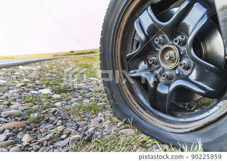 Close up of flat tire on a car on gravel road. Close up of flat tire on a car on gravel road. 90225959