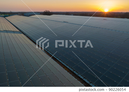 Blue photovoltaic solar panels mounted on building roof for producing clean ecological electricity at sunset. Production of renewable energy concept 90226054