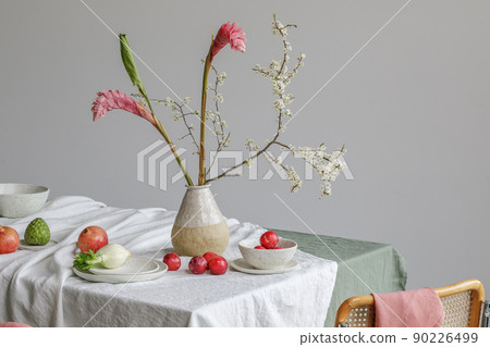 Elegant table setting with cherry brunch in craft vase , cherimoya fruits, fenel and plums in craft ceramic plate on linen tablecloth. Outdoor table setting for summer holiday concept. 90226499