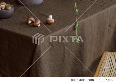 Elegant table setting with green brunches, brown champignons in craft ceramic plate on linen tablecloth. Outdoor table setting for summer holiday concept. 90226500
