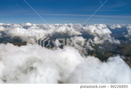 Aerial view from airplane window at high altitude of earth covered with white puffy cumulus clouds. Aerial view from airplane window at high altitude of earth covered with white puffy cumulus clouds. 90226893