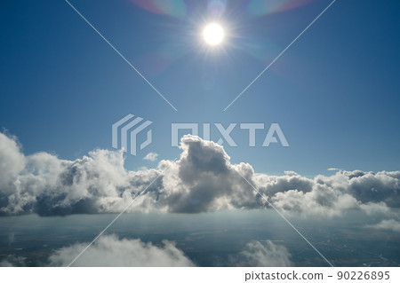 Aerial view from airplane window at high altitude of earth covered with puffy cumulus clouds forming before rainstorm Aerial view from airplane window at high altitude of earth covered with puffy cumulus clouds forming before rainstorm 90226895