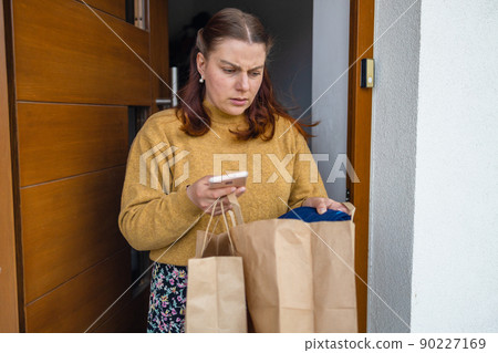 50s woman hands take a parcel by her self at home. Package on the floor by the door. Quarantine and isolation. Coronavirus concept 90227169