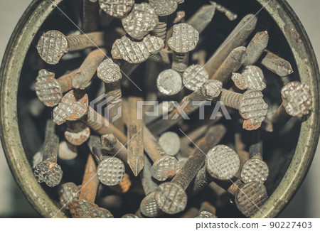 Old iron nails close-up in an iron jar. Iron pin covered with dust and rust. Selective focus, grain 90227403
