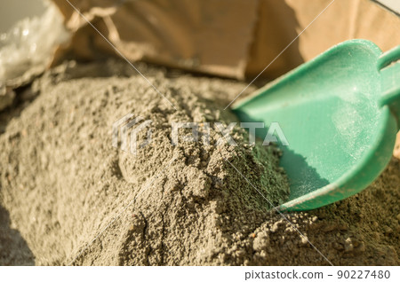Grey sand-concrete dry mix in an open paper bag. Concrete dry powder for leveling walls and floors. Repair in the house with your own hands. DIY. Selective focus Grey sand-concrete dry mix in an open paper bag. Concrete dry powder for leveling walls and floors. Repair in the house with your own hands. DIY. Selective focus 90227480